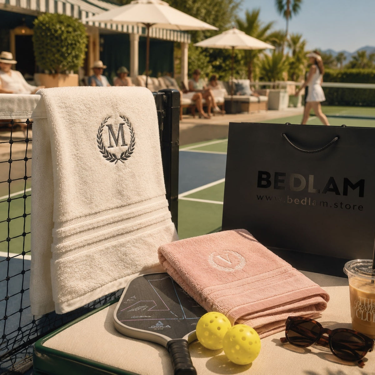 Monogram bath towel with wreath initial and blush pink towel by a tennis court – BEDLAM personalised towels