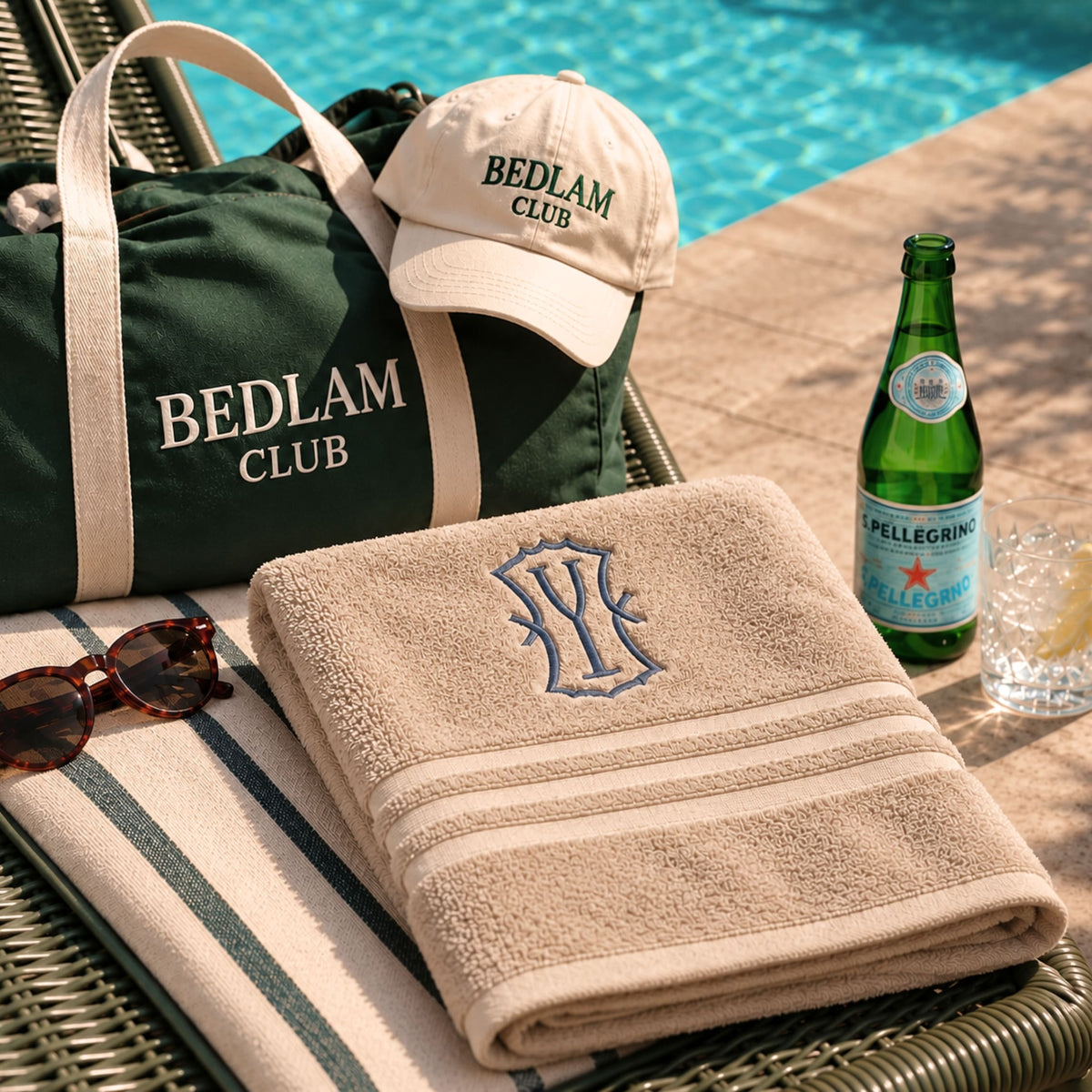 Beige organic cotton monogram bath towel with embroidered initials, poolside on a lounger – BEDLAM